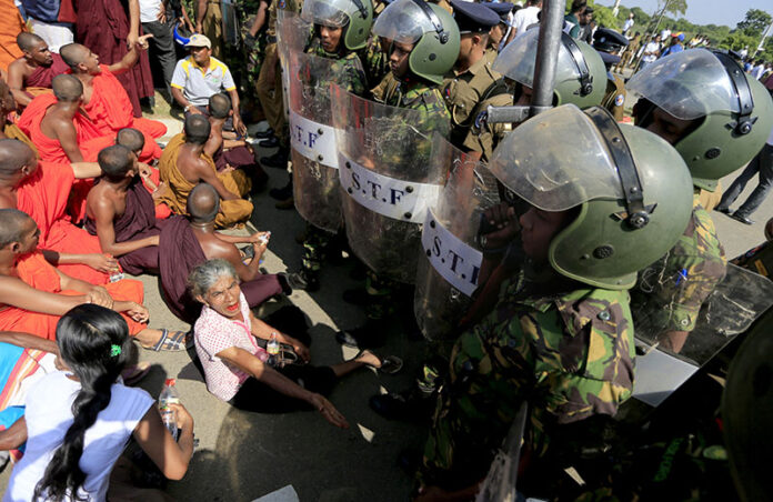 Sri Lankan Buddhist monks and villagers face soldiers and shout slogans on Jan. 7, 2017, to protest a plan to take over private land for an industrial zone in which China will have a major stake outside the inauguration ceremony for the industrial zone in Mirijjawila village in Ambalantota, Sri Lanka. Photo: Eranga Jayawardena / Associated Press