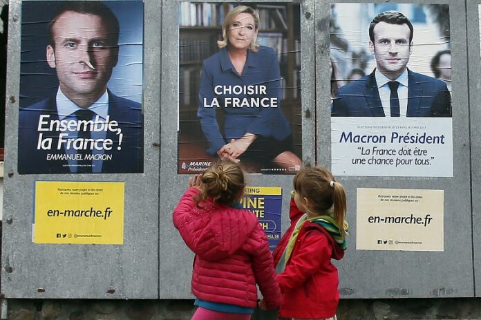 Children walk past election campaign posters for French centrist presidential candidate Emmanuel Macron and far-right candidate Marine Le Pen, Friday in Osses, southwestern France. Photo: Bob Edme / Associated Press