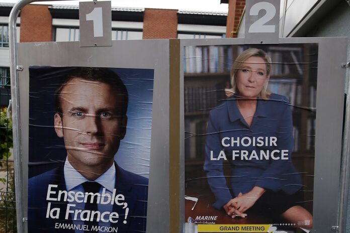 Election campaign posters for French centrist presidential candidate Emmanuel Macron and far-right candidate Marine Le Pen are displayed in front of the polling station where Marine Le Pen will vote, Saturday in Henin Beaumont, northern France. Photo: Francois Mori / Associated Press