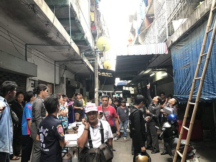 Police, emergency officials and neighbors crowd around a flat Tuesday in Yan Nawa district where a newborn’s body was found on an exposed ledge.