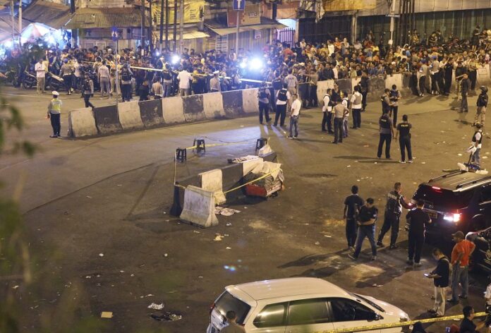 Police officers clear the area around the site of an explosion Wednesday night in Jakarta, Indonesia. Photo: Dita Alangkara / Associated Press
