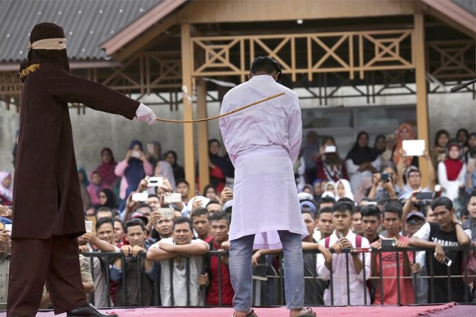 A Sharia law official whips a man convicted of adultery with a rattan cane in 2017 in Banda Aceh, Indonesia. Photo: Heri Juanda / Associated Press