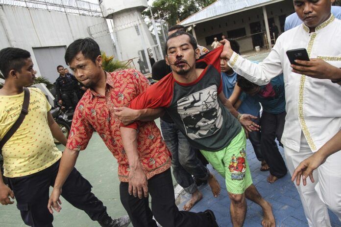 Plain-clothed police officers escort recaptured inmates following their escape at Sialang Bungkuk Prison on Friday in Pekanbaru, Riau province, Indonesia. Photo: Associated Press