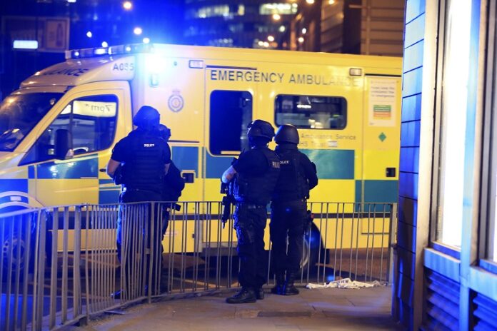 Armed police stand next to an ambulance after an explosion at the Manchester Arena on Tuesday in Manchester, England. Photo: Peter Byrne / Associated Press