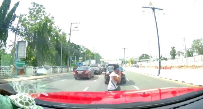 Sudchada Buripia talks on her mobile phone as she crosses a road Wednesday in Chonburi province moments before she was struck by a speeding car.