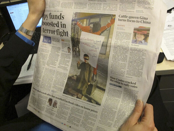 A 6-year-old Australian boy makes an Islamic State salute in front of a human body hanging from a cross somewhere in the Middle East on Monday's front page of