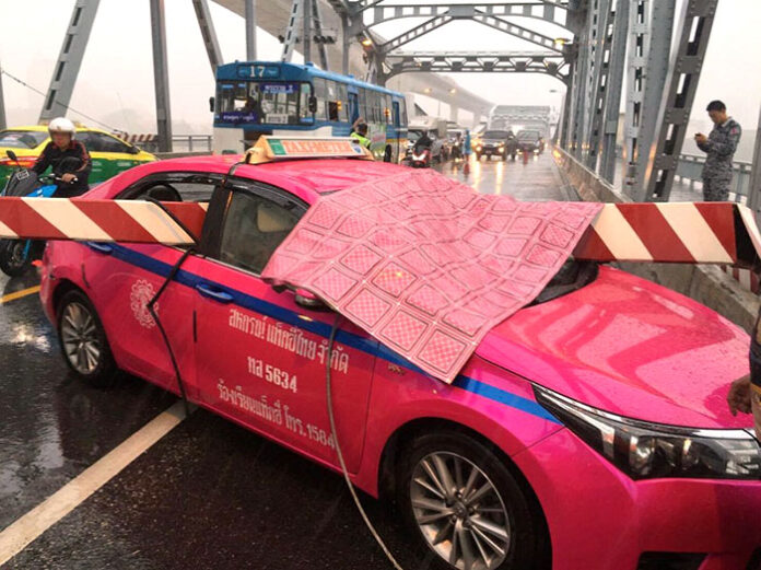 A taxi crashed into a barrier gate on the Krungthep Bridge Tuesday morning amid heavy rain.