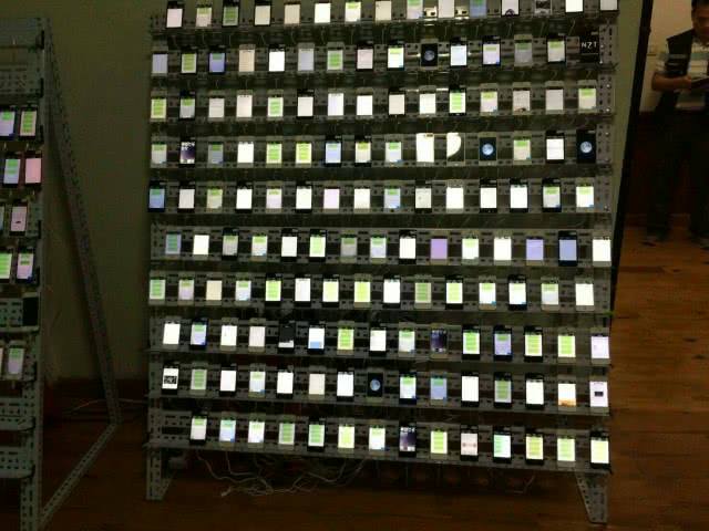 A bank of dozens of phones are lined up on a shelf inside a house police raided Sunday in Sa Kaeo province. Photo: Jiggie Jaa / Facebook