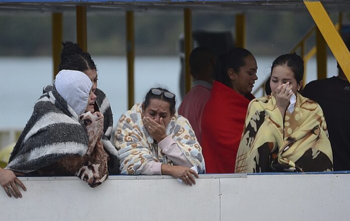 People who survived a sunken ferry, cry as they wait for more information about their missing friends and relatives, Sunday at a reservoir in Guatape, Colombia. Photo: Luis Benavides / Associated Press