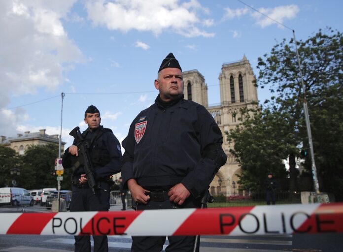 Police officers seal off the access to Notre Dame cathedral, seen in the background, after a man attacked officers with a hammer outside the famous landmark Tuesday, in Paris, France. Photo: Christophe Ena / Associated Press