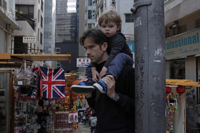 A man carrying a child walks past a British flag in March in Hong Kong. Photo: Kin Cheung / Associated Press