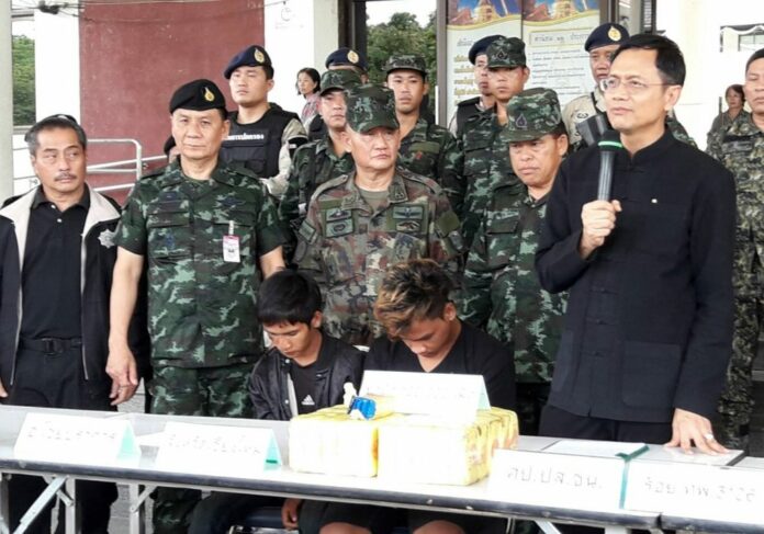 Police and military officers bring two drug suspects to a news conference on June 14 in Chiang Mai province.