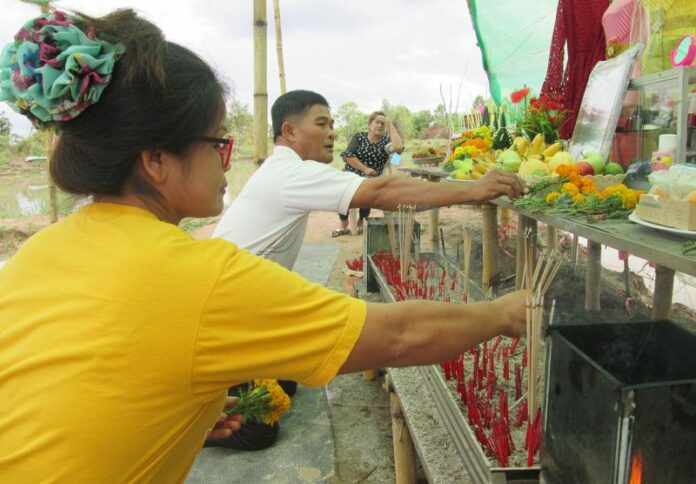 Residents offer incense sticks to a mango tree Thursday in Nakhon Phanom.