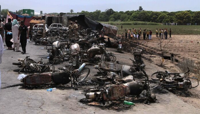 Pakistan army soldiers stands guard while rescue workers examine the site of an oil tanker explosion at a highway Sunday near Bahawalpur, Pakistan. Photo: Iram Asim / Associated Press