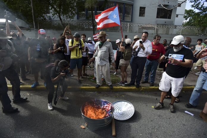 Protesters in favor of Puerto Rico's independence protest after a referendum was held on the island's status by burning a U.S. flag in the financial district, known as the golden mile, Sunday in San Juan, Puerto Rico. Photo: Carlos Giusti / Associated Press