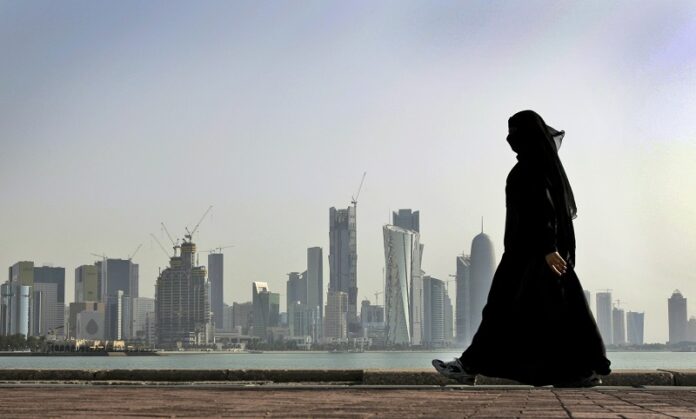 A Qatari woman walks in front of the city skyline in 2010 in Doha, Qatar. Photo: Kamran Jebreili / Associated Press