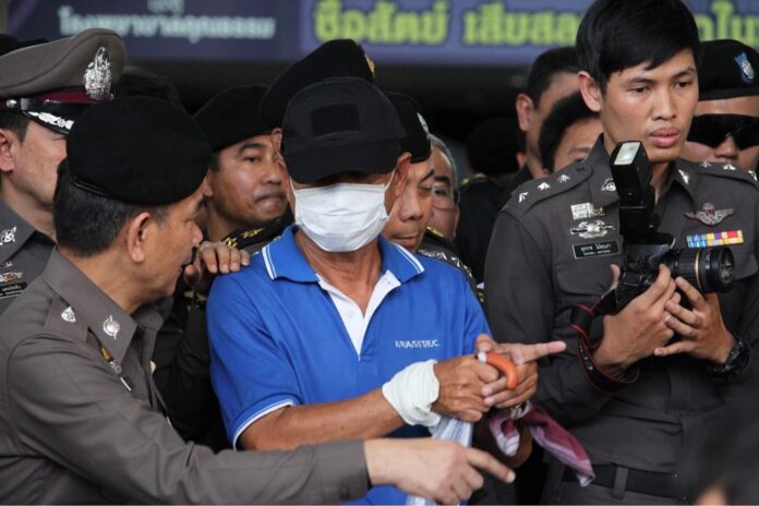 Flanked by soldiers and police, Wattana Pumares tells a policeman Tuesday how he allegedly carried out the bomb attack at Phramongkutklao Hospital last month.