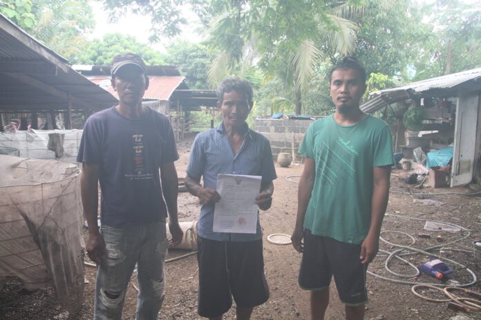 Suthin Poonsawat shows reporters Monday a court warrant that misidentified him as a defendant in a theft case.