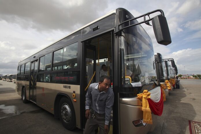 A Cambodian man gets off one of the buses donated by China to Cambodia prior to a handover ceremony Thursday in Phnom Penh, Cambodia. Photo: Heng Sinith / Associated Press