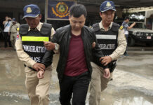 More Than 200 Chinese Arrested in Cambodia for Online Scams A Chinese national arrested over an alleged internet scam is escorted by police on his way to deportation at the immigration office in 2017 in Phnom Penh. Photo: Heng Sinith / Associated Press