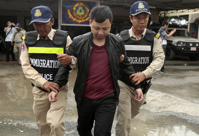 A Chinese national arrested over an alleged internet scam is escorted by police on his way to deportation at the immigration office in 2017 in Phnom Penh. Photo: Heng Sinith / Associated Press