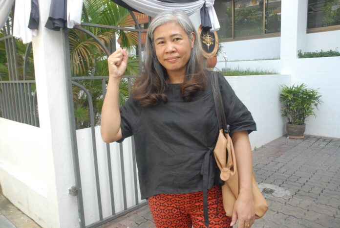 Former labor activist Jittra Cotchadet gestures Thursday in front of the military court in Bangkok