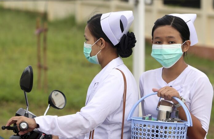 Nurses cover their faces with masks to protect from the spread of the swine flu Tuesday outside the Naypyitaw hospital. Photo: Aung Shine Oo / Associated Press