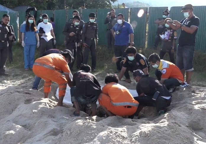 Rescue workers unearth body of an unidentified woman from a beach on Samui island Monday afternoon.