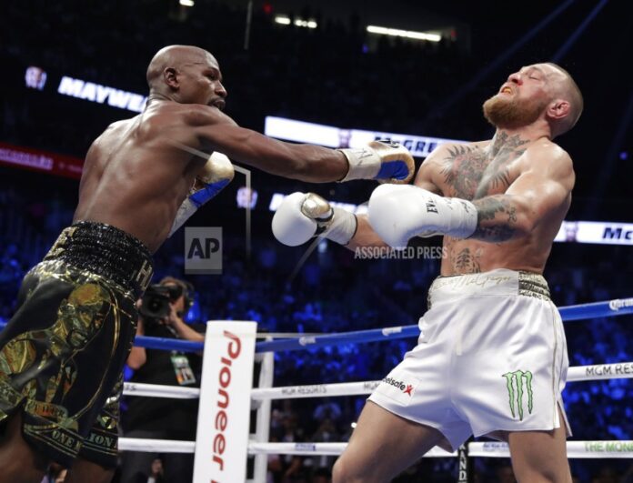 Floyd Mayweather Jr. hits Conor McGregor in a super welterweight boxing match Saturday in Las Vegas. Photo: Isaac Brekken / Associated Press