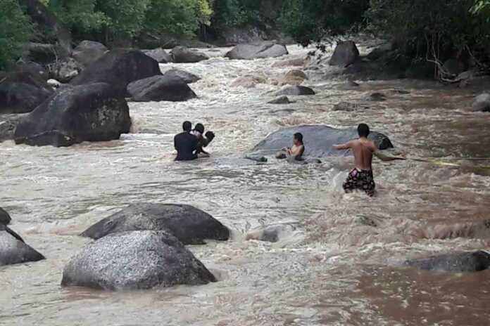 Emergency officials and resident men rescue a stranded family from the Na Bon River.