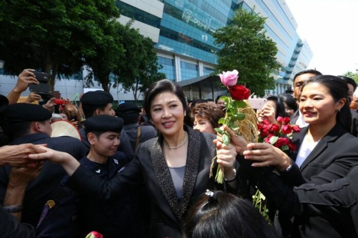 Former premier Yingluck Shinawatra accepts flowers from her supporters Friday outside the Supreme Court in Bangkok.