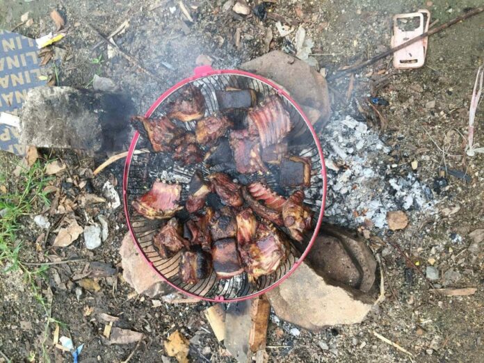 Pieces of what’s alleged to be dog meat smoke over a makeshift grill Tuesday in Hat Yai.