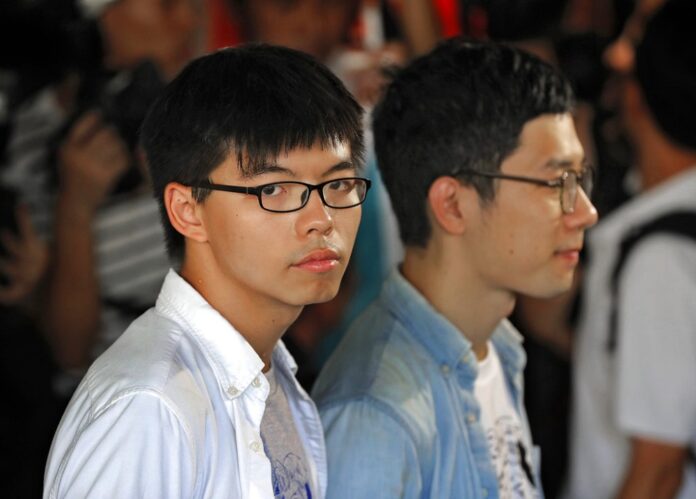 Hong Kong activist Joshua Wong, left, and Nathan Law, right, speak outside the high court before an ruling on a prosecution request for stiffer sentences following a lower court decision that let them avoid prison, in August in Hong Kong. Photo: Vincent Yu / Associated Press