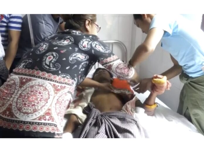 In this image made from video, a man lying on a bed with a bandaged hand is cared for Friday in a hospital in Buthidaung township, Myanmar. Photo: Associated Press