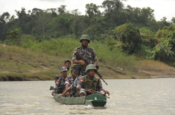 Myanmar Border Guard Police (BGP) officers travel in a wooden boat operated by Rohingya Muslim men in July at Tin May village in which Myanmar government and military claim the existence of alleged Muslim terrorists in Buthidaung, Rakhine State, Myanmar. Photo: Esther Htusan / Associated Press