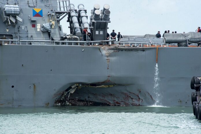 Damage to the portside is visible as the Guided-missile destroyer USS John S. McCain (DDG 56) steers towards Changi naval base Monday in Singapore following a collision with the merchant vessel Alnic MC. Photo: Joshua Fulton / Associated Press