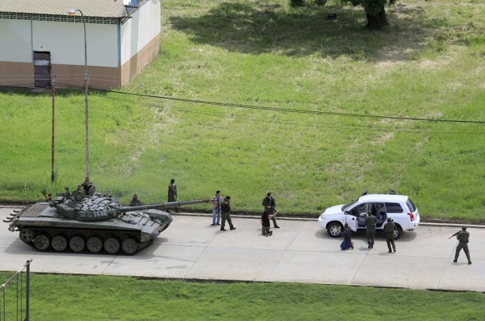 Soldiers stop a vehicle, whose passengers kneel on the ground outside the car, as they detain the two passengers who were circulating on the Paramacay military base Sunday in Valencia, Venezuela. Photo: Juan Carlos Hernandez / Associated Press