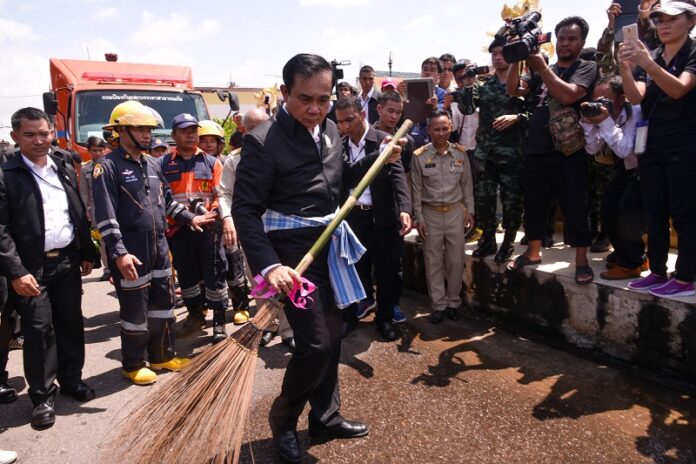 Prime Minister Prayuth Chan-ocha joins a clean-up event after water levels fell Wednesday in Sakon Nakhon province.