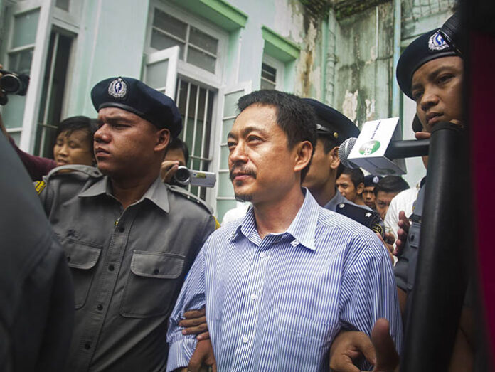 Kyaw Min Swe, at center, chief editor of The Voice Daily newspaper, is escorted by police on June 16, 2017, during a trial at the township court in Yangon. Photo: Thein Zaw / Associated Press
