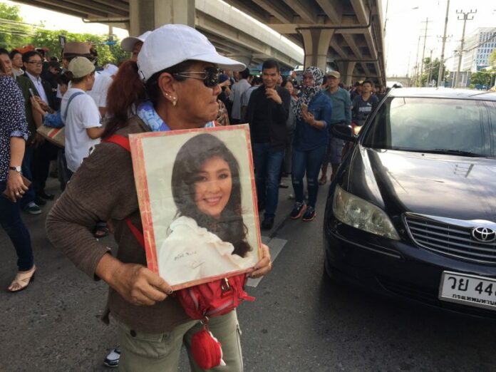 A supporter of former PM Yingluck Shinawatra holds a portrait of her Friday near the Supreme Court.