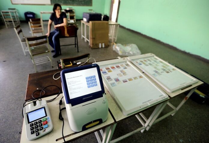 A member of the Venezuelan National Electoral Council waits for a voting machine to charge during the preparation of a polling station in 2013 in Caracas, Venezuela. Photo: Fernando Llano / Associated Press