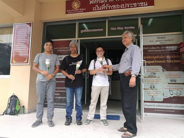 Online news editor Teeramon Bua-ngam, at far left, and university anthropologist Chayan Vaddhanaphuti, at far right, and two others stand Monday outside the Changpuak Police station in Chiang Mai city.