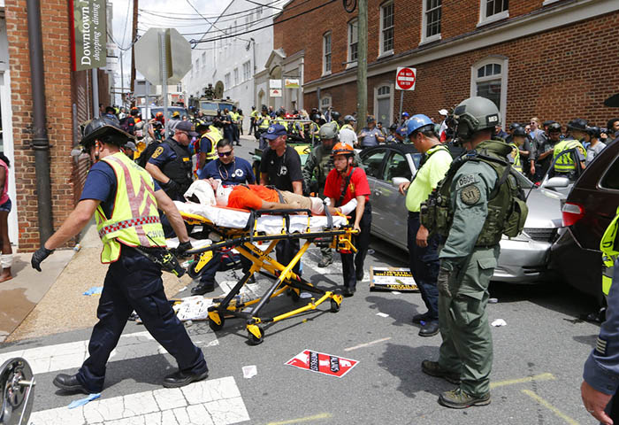 Rescue personnel help injured people after a car ran into a large group of protesters Saturday after a white nationalist rally in Charlottesville. Photo: Steve Helber / Associated Press