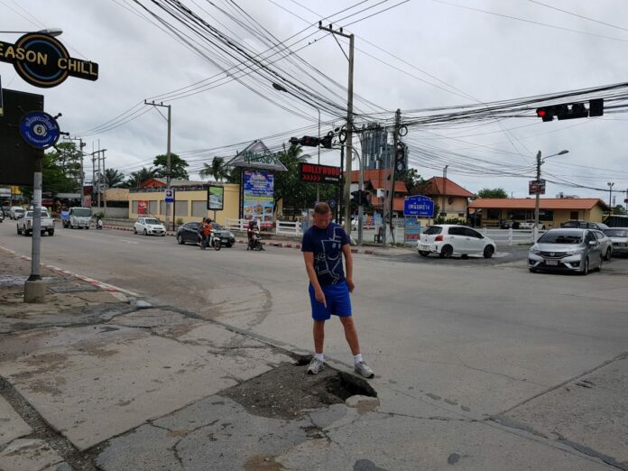 A foreigner points out a hole Sunday in the Paniet Chang Road intersection in Pattaya.
