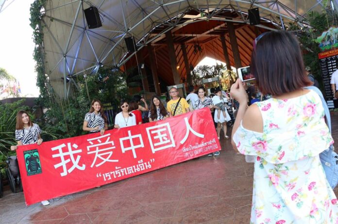 Chinese tourists pose with a sign reading “We Love Chinese People” in front of Chiang Mai Zoo in July 2016.