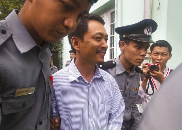 Kyaw Min Swe, center, chief editor of The Voice Daily newspaper, is escorted by police in June for his trial at the township court in Yangon, Myanmar. Photo: Associated Press
