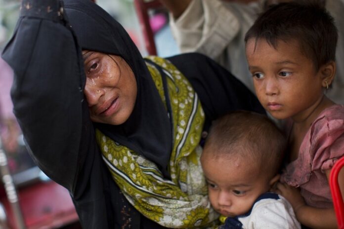 An exhausted Rohingya woman arrives with her children at Kutupalong refugee camp after crossing from Myanmmar to the Bangladesh side of the border in September in Ukhia. Photo: Bernat Armangue / Associated Press