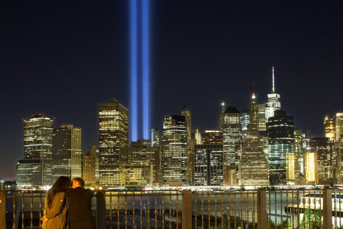 A couple embraces on the Brooklyn Promenade as the Tribute in Light rises above the lower Manhattan skyline in 2017 in New York. Photo: Mark Lennihan / Associated Press