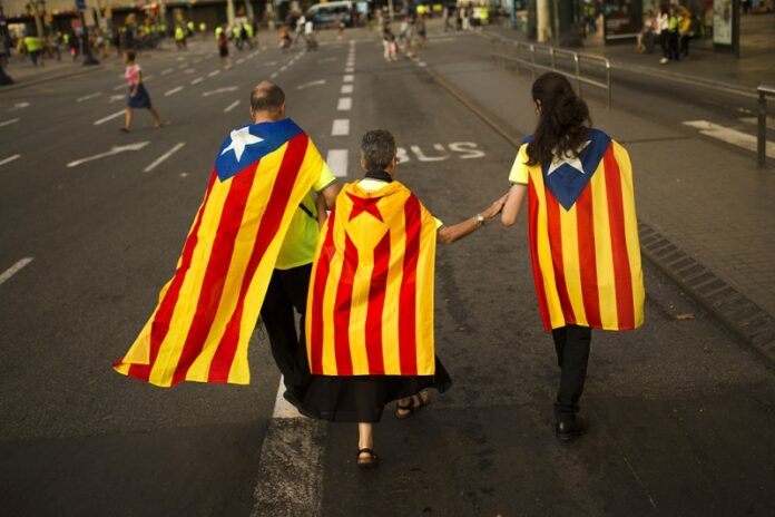 Family members wearing estelada or independence flags on their back walk at the end of a big rally Monday during the Catalan National Day in Barcelona, Spain. Photo: Francisco Seco / Associated Press
