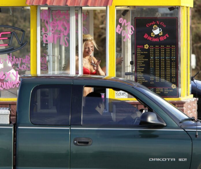 FILE - In this Feb. 2, 2010, file photo, a barista at a Grab-N-Go Bikini Hut espresso stand holds money as she waves to a customer, just outside the city limits of Everett, Wash., in Snohomish County. Photo / Ted S. Warren / Associated Press